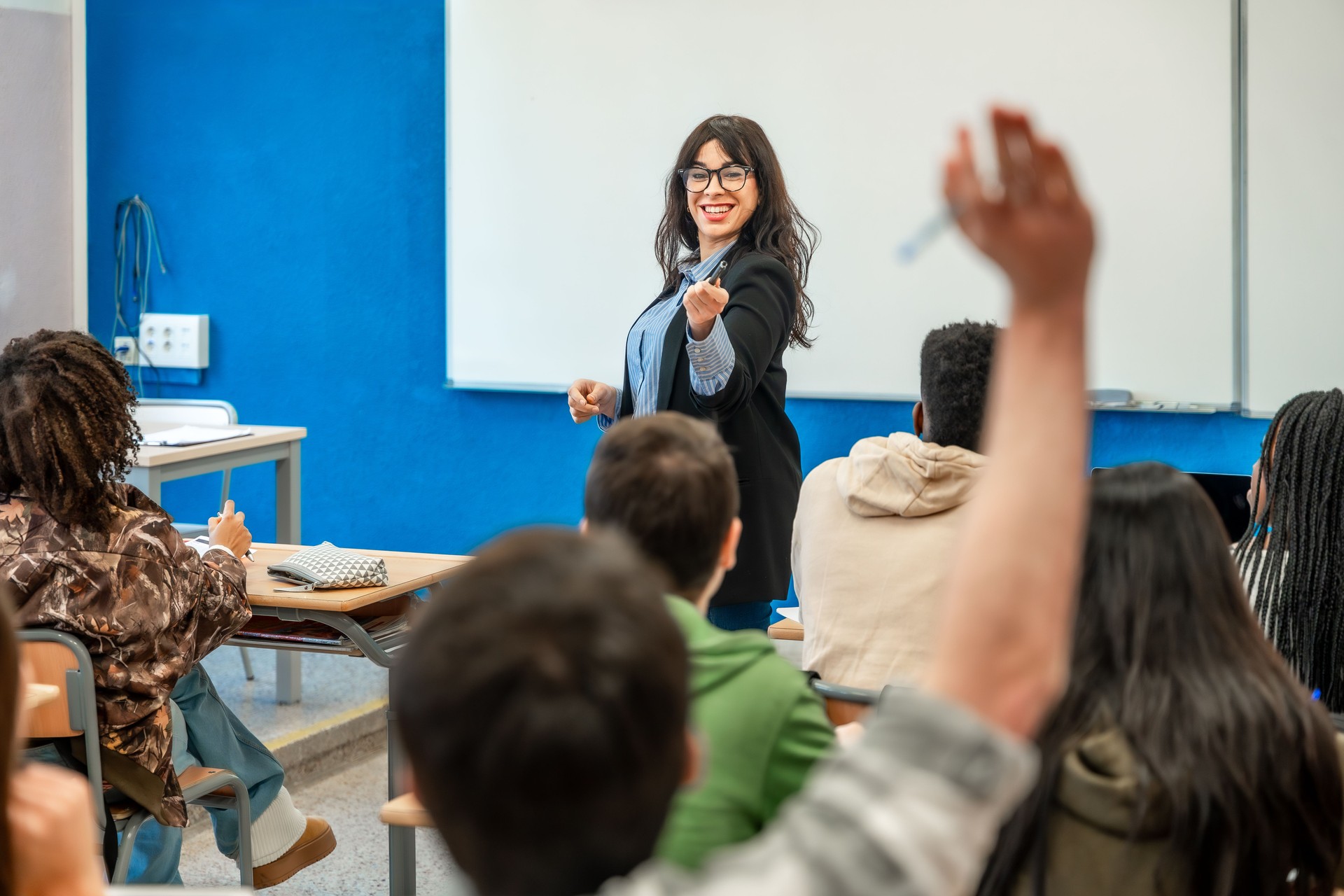 Smiling teacher picking a student to answer in classroom